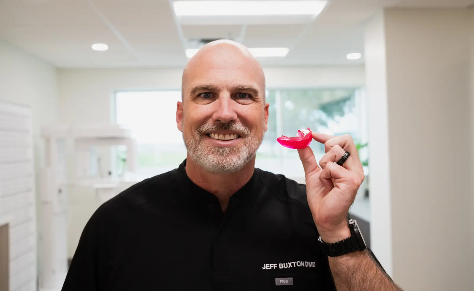 Dr. Jeff Buxton smiling and holding a removable growth appliance used for younger kids