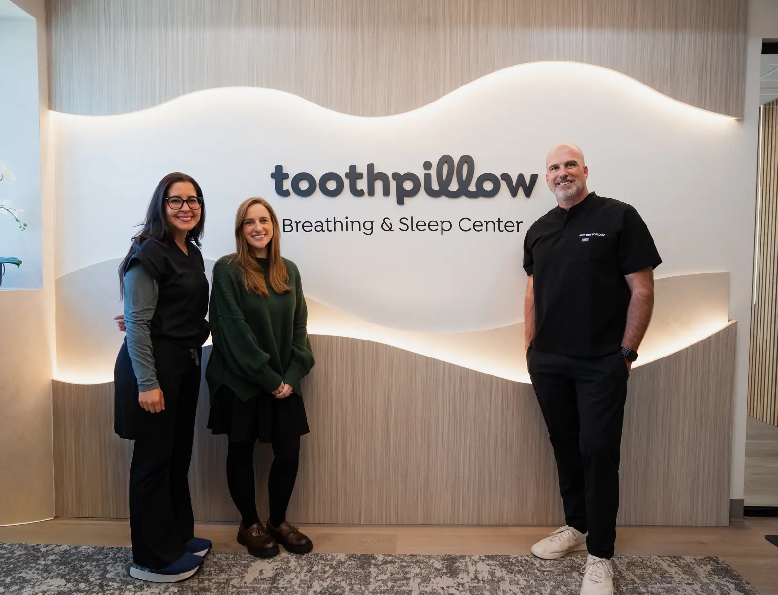 Dr. Jeff Buxton and the team in front of the Toothpillow Breathing and Sleep Center sign in Draper, Utah